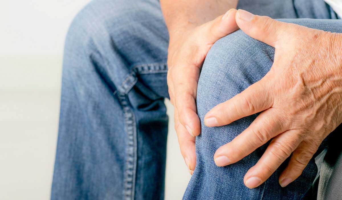 Man holds his knee after having had double knee replacement surgery