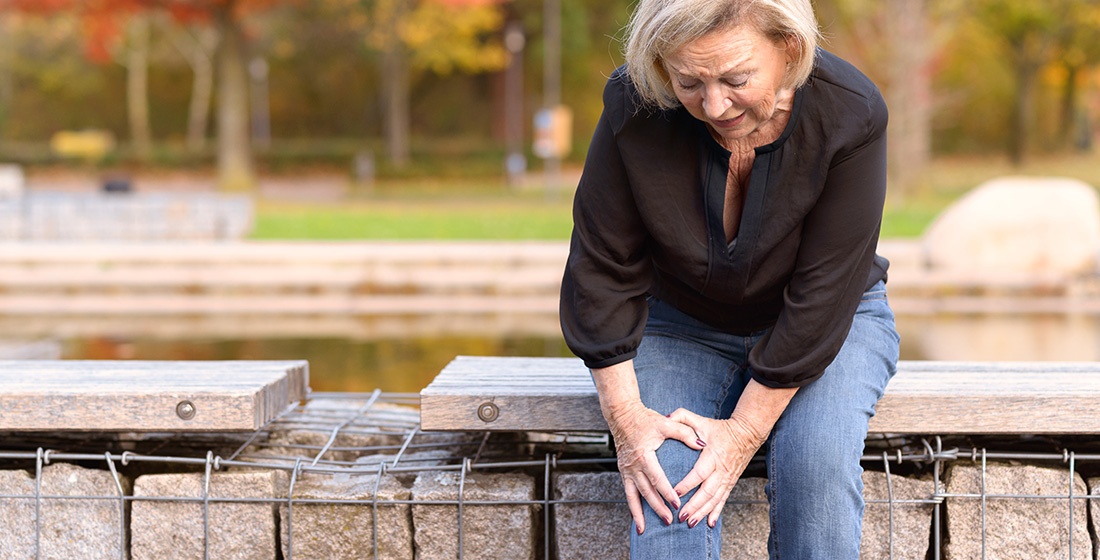 Elderly woman holding knee in pain