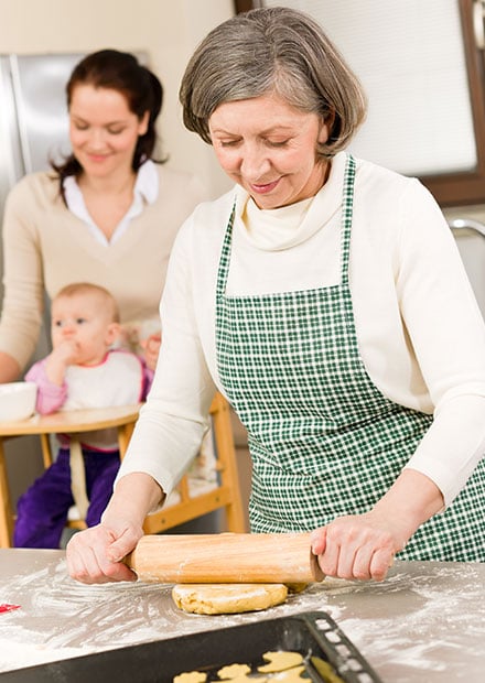 Grandmother rolling out dough in kitchen