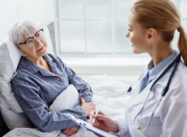 Elderly woman in hospital bed listening to doctor speak