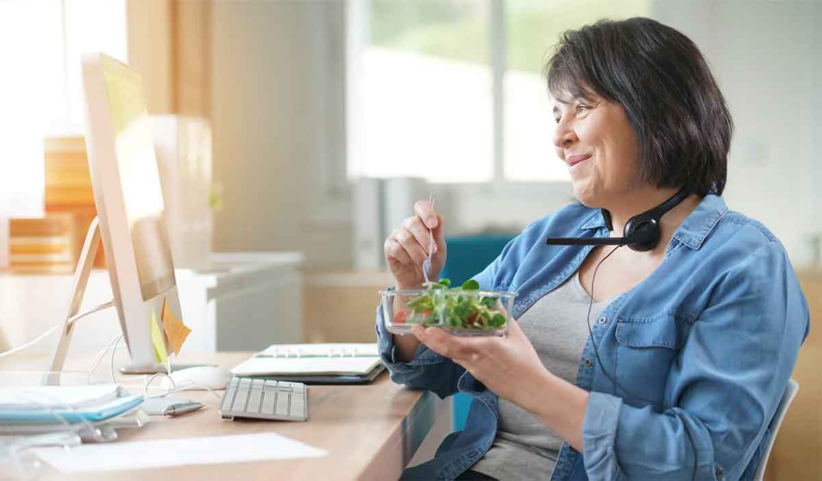 Woman eats a healthy lunch while chatting online with her weight-loss coach